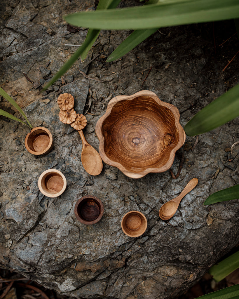 birds eye view of a Wooden daisy bowl, flower spoon, mini pots and a mini spoon sitting on a slate rock