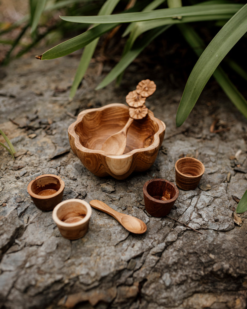 front on view of a Wooden daisy bowl, flower spoon, mini pots and a mini spoon sitting on a slate rock