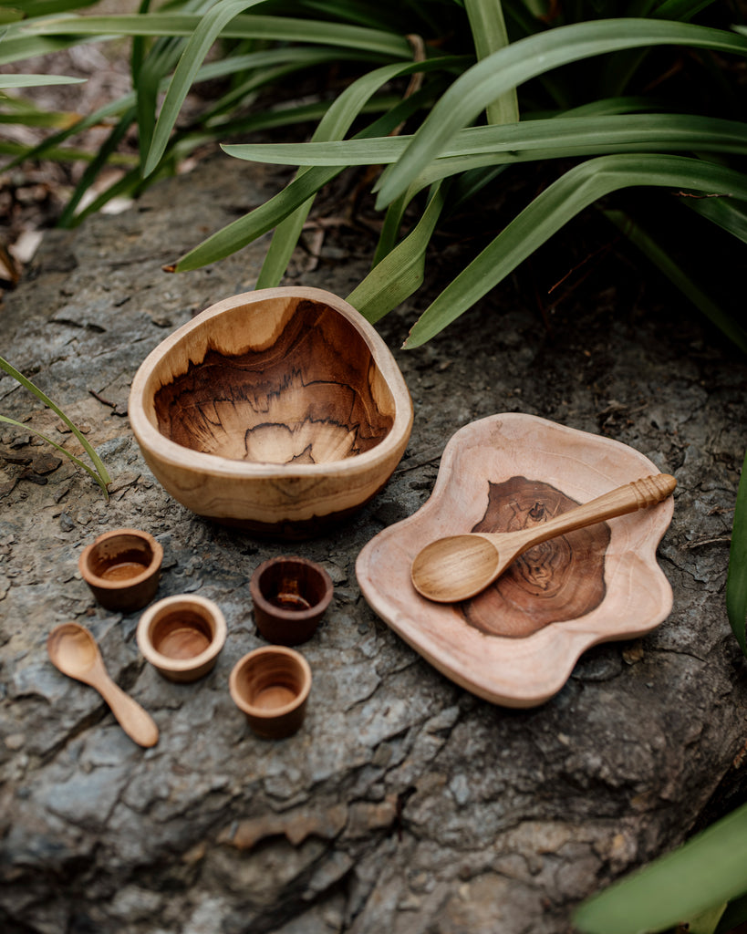 wooden bowl, plate, 4 wooden mini bowls and a spoon on a slate rock