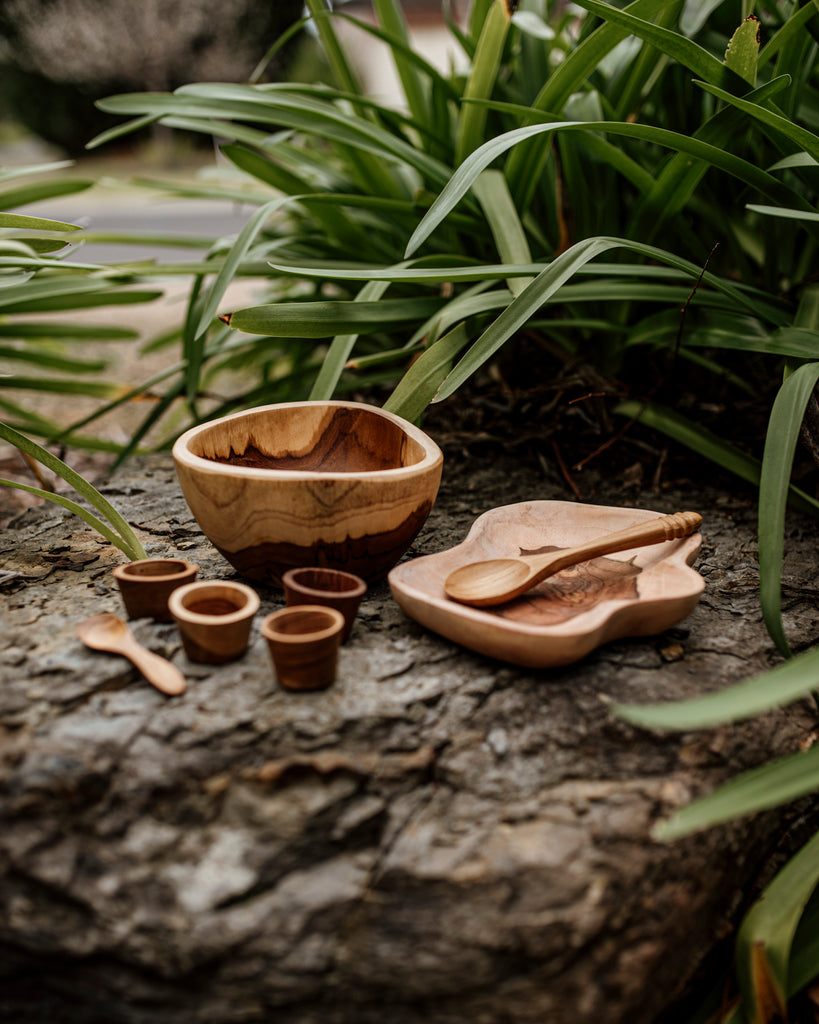 wooden bowl, plate, 4 wooden mini bowls and a spoon on a slate rock